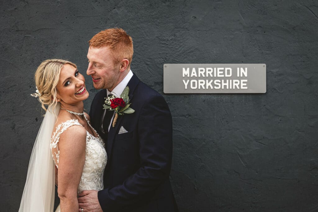 A Bride and groom at wharfdale grange with a sign behind saying Married in yorkshire | West yorkshire wedding photography