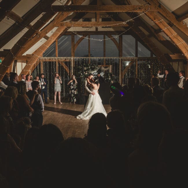 Bride & groom first dance at sandburn hall hotel with large glass windows in the background with all guests cirlced watching