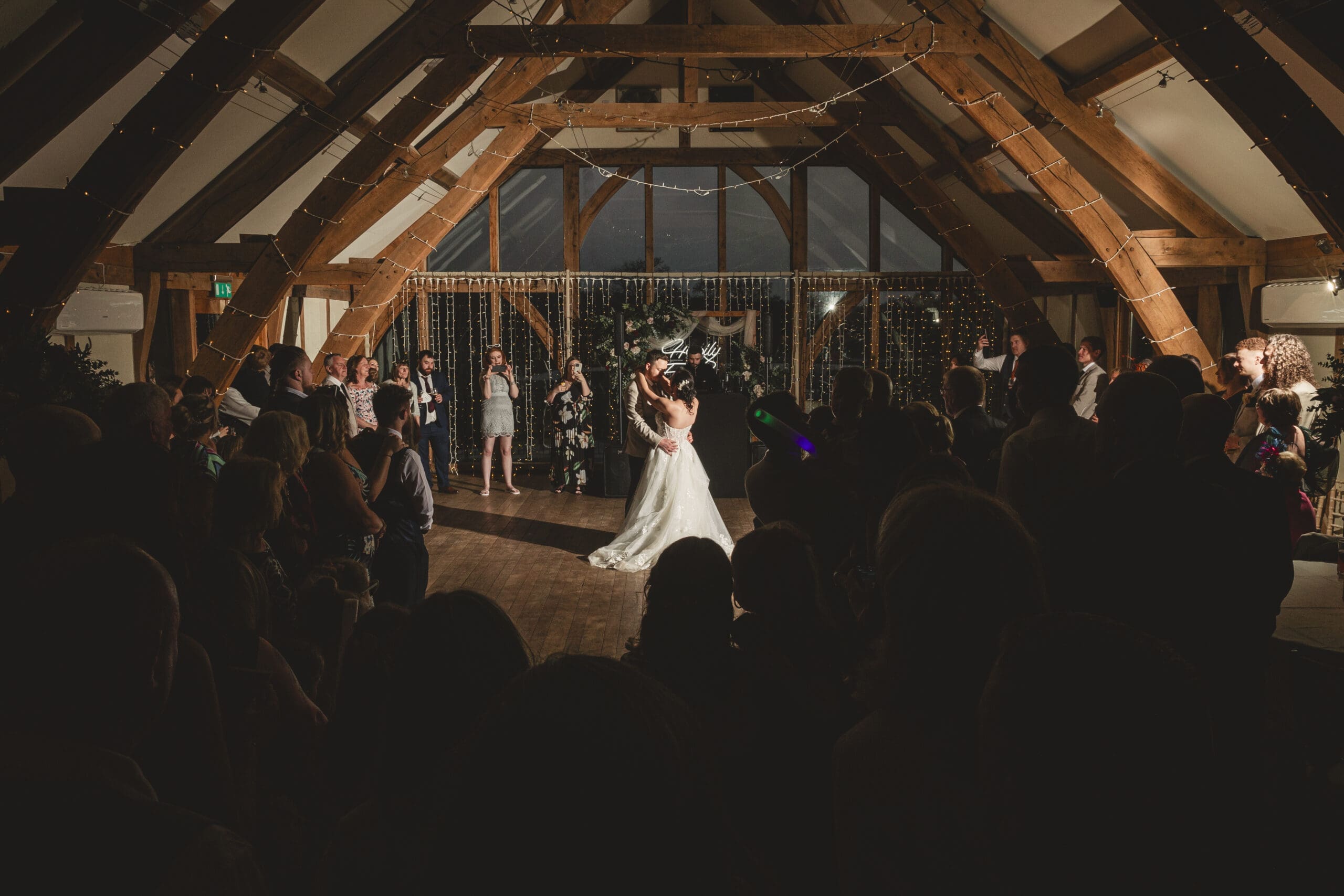 Bride & groom first dance at sandburn hall hotel with large glass windows in the background with all guests cirlced watching