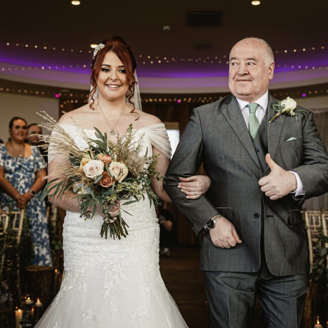 Bride with red hair walkign down aisle in ceremony at outbarn clitheroe