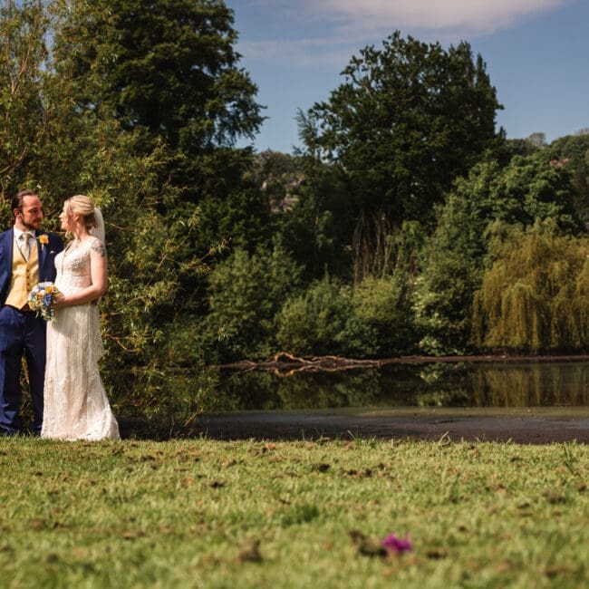 A bride & groom on there wedding overlooking the lakeside at east riddlesden hall