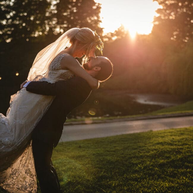 A bride and groom at sunset taken at east riddlesden hall - the groom is picking the bride up as the golden sun shines behind | East riddlesden Hall wedding photographer