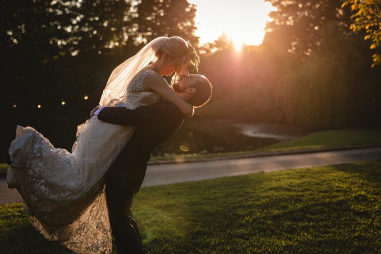 A bride and groom at sunset taken at east riddlesden hall - the groom is picking the bride up as the golden sun shines behind | East riddlesden Hall wedding photographer