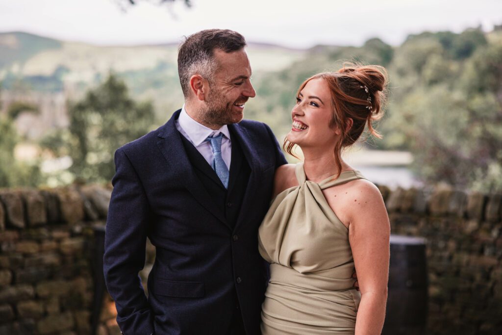 A Couple of guests sharing a photo - witth the girl in a sage green bridesmaids outfit at the tithe barn