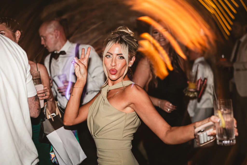 Bridesmaid dancing at the tithe barn in a sage green bridesmaid dress