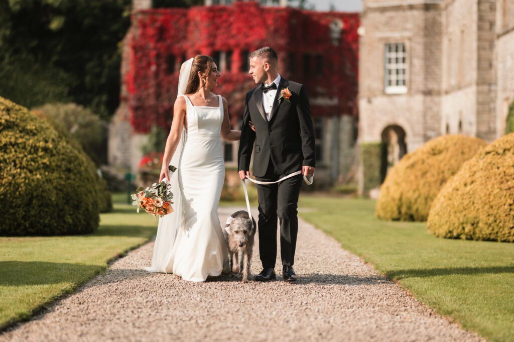 Bride & Groom and dog walking away from tissington hall | Yorkshire Wedding Photographer