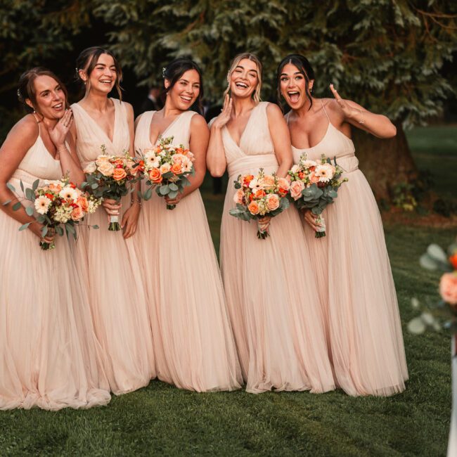 Bridesmaids with autumn flowers looking happy at the bride with golden sun in the gardens of the Tithe Barn | Tithe barn wedding photographer