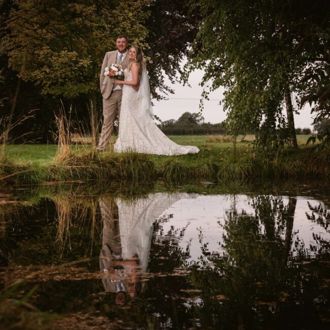 A couple standing at a lake at deighton lodge with a beautiful reflection in the lake | Yorkshire Wedding Photographer