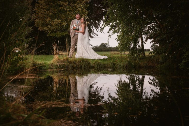 A couple standing at a lake at deighton lodge with a beautiful reflection in the lake | Yorkshire Wedding Photographer