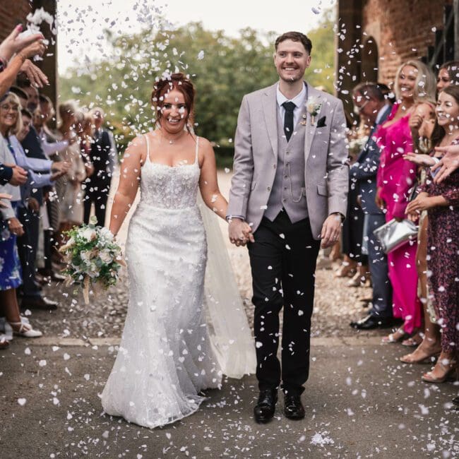 bride and groom walking through conffeti tunnel at hodsock priory