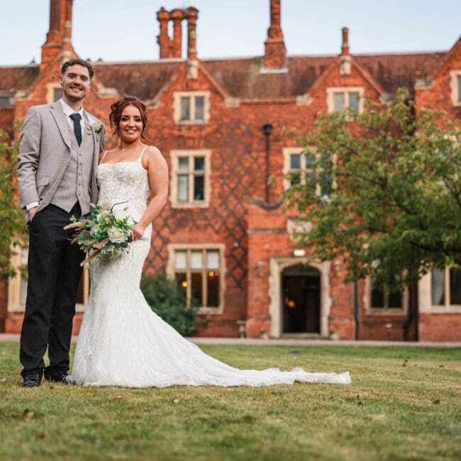 Bride and groom posing for a photo at hodsock priory with venue in the background | Hodsock priory wedding photographer