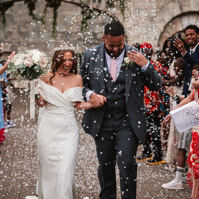 White conffeti being thrown at hazzlewood castle as the bride and groom walk through | Hazzlewood wedding photographer