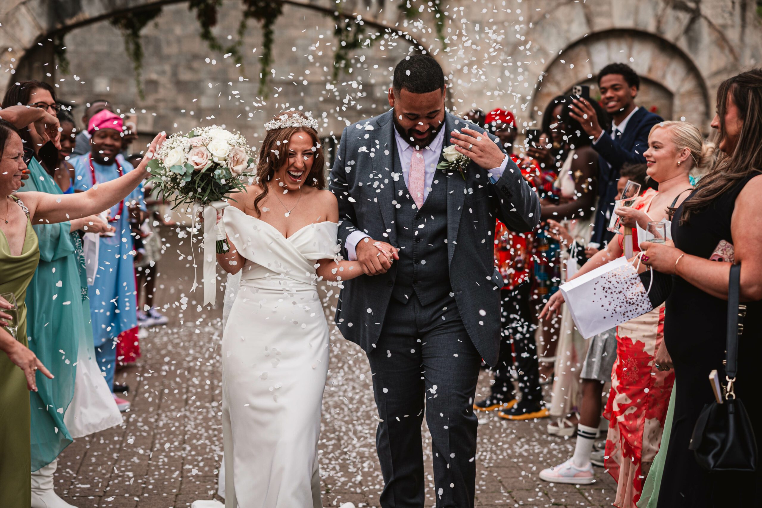 White conffeti being thrown at hazzlewood castle as the bride and groom walk through | Hazzlewood wedding photographer