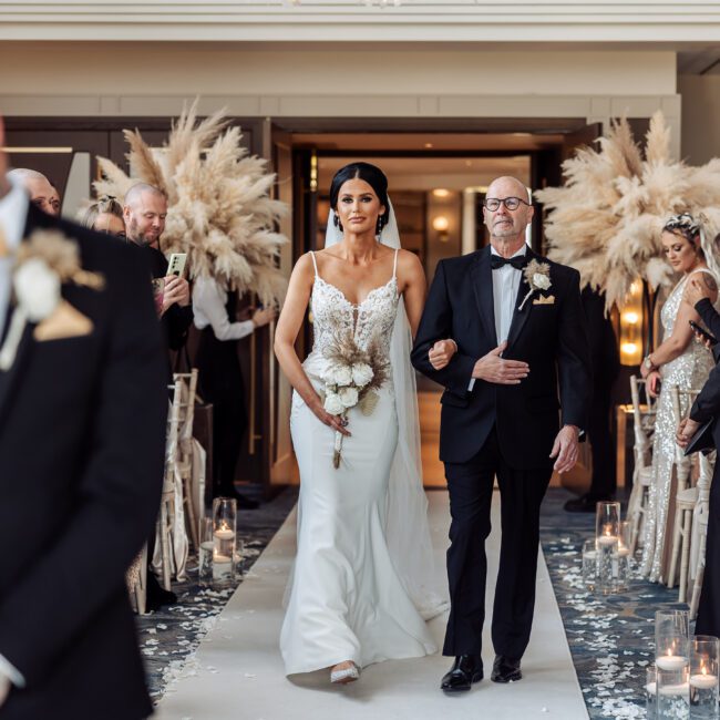 bride walking down aisle as groom emotionally waits at the front at crow wood hotel and spa