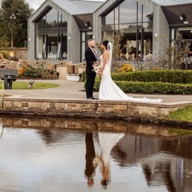 bride and groom along side lake at crow wood hotel spa