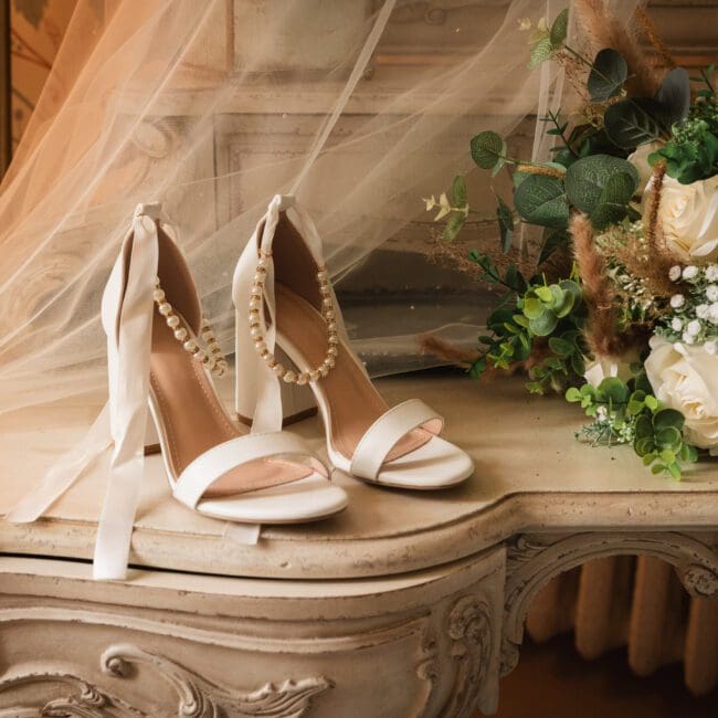 Brides shoes on a vanity table with her veil behind in the bridal prep room at hodsock priory | Hodsock priory wedding photographer